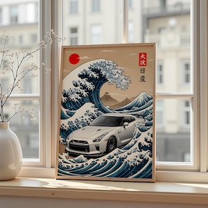 Puede incluir: Impresión enmarcada que presenta un coche deportivo blanco en medio de un diseño de olas japonesas estilizadas. La obra de arte incluye un sol rojo, montañas y texto japonés. El coche es el punto focal, sobre un fondo de tonos azules y beige.