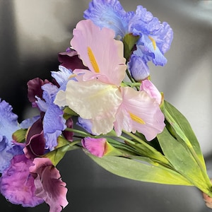 May include: A bouquet of artificial iris flowers in shades of purple, blue, and pink. The flowers have delicate petals and are arranged in a cluster.
