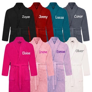 May include: Eight plush bathrobes in various colours, each with a different name embroidered on the front. The names are: Zayan, Jonny, Lucas, Conor, Eloise, Irene, Esmae, and Oliver.
