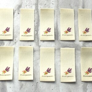 May include: Ten beige fabric labels with a purple flower design and the text "Anaispassion" printed on each.