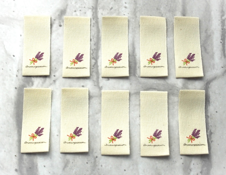 May include: Ten beige fabric labels with a purple flower design and the text "Anaispassion" printed on each.