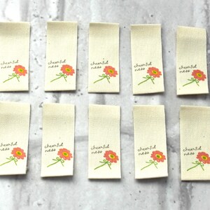 May include: Ten off-white fabric tags with a pink flower and the text "cheerfulness" printed on each.
