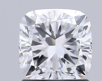 May include: A close-up of a cushion-cut diamond. The diamond is white and has many facets that reflect light. The shape is square with rounded corners. The diamond is set against a light gray background.