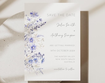 Puede incluir: Una tarjeta rectangular blanca de Save the Date con una ilustración en acuarela de flores silvestres azules y moradas a lo largo del borde izquierdo. El texto dice: SAVE THE DATE, Julie Smith + Anthony Simpson, ARE GETTING MARRIED, 19TH OCTOBER 2024, THE HUNTER VALLEY, NEW SOUTH WALES, AUSTRALIA, invitation to follow.