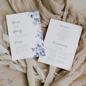 May include: Wedding ceremony programme fans with a blue floral design. The fans feature the names Annie and Henry, the wedding date, and the order of service. The back of the fan includes a thank you message to guests.