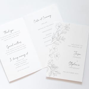 May include: A wedding stationery set, including a folded order of service and a welcome card. The cards are white with black text and a floral illustration. The welcome card displays the names of the couple.