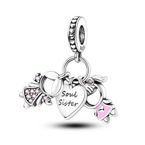 May include: Silver charm with two angel figures, a heart with the inscription "Soul Sister", and a pink heart. The charm has a silver loop for attaching to a bracelet or necklace.