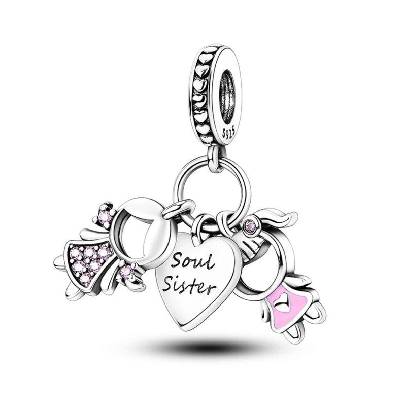 May include: Silver charm with two angel figures, a heart with the inscription "Soul Sister", and a pink heart. The charm has a silver loop for attaching to a bracelet or necklace.