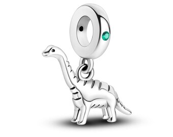 May include: Silver charm featuring a detailed dinosaur with a green gemstone accent. The charm has a loop for attaching to a bracelet or necklace.