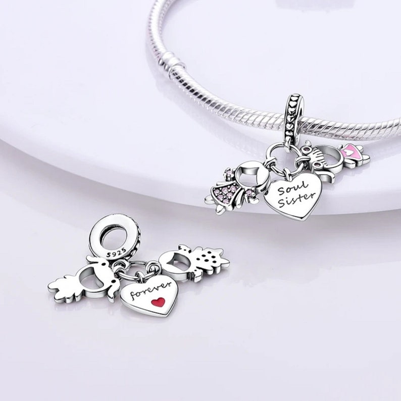 May include: Silver charm bracelet with two charms. One charm features two girls holding hands with a heart that says "forever" and the other charm features two girls holding hands with a heart that says "Soul Sister".
