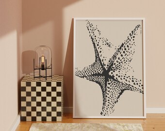 May include: A black and white illustration of a starfish on a beige background. The illustration is framed in a white frame and is hanging on a wall above a black and white checkered side table.