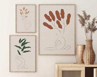 May include: Three minimalist line art prints featuring a woman in a yoga pose with leaves growing from her head. The prints are framed in a light wood frame and hung on a white wall.