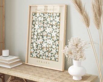 May include: A framed print with a floral design. The print features a pattern of white flowers on a green background. The frame is brown wood and the print has the title "FLOWER MARKET" and the word "ANKARA" at the bottom.