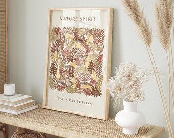 May include: Framed wall art featuring a botanical leaf pattern in shades of brown, gold, and white. The artwork is labeled "NATURE SPIRIT" and "LEAF COLLECTION". The frame is light-colored wood. The artwork is displayed on a light-colored bench with decorative items.