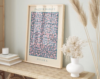 May include: A framed print with a blue background and a pattern of pink flowers. The print has the text "FLOWER MARKET" and "OSAKA" on it.