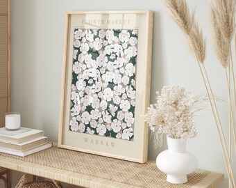 May include: A framed print with a floral design featuring white flowers on a dark green background. The print has the text "FLOWER MARKET" and "WARSAW" on it.