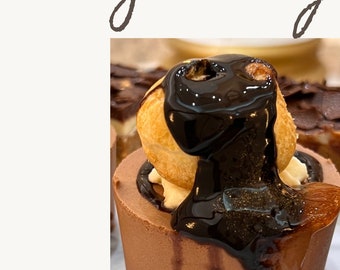 May include: A close-up of a chocolate dessert topped with a cream puff and drizzled with chocolate sauce. The dessert is on a white surface and the word "Yummy" is written above and below the image.
