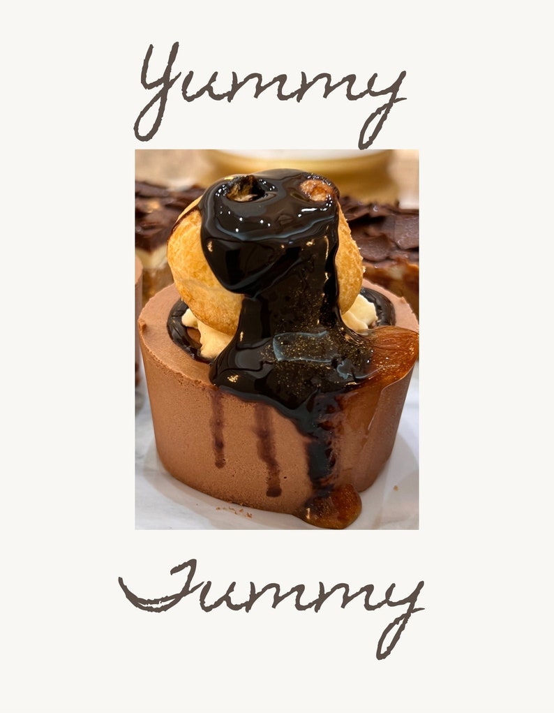 Pu&ograve; includere: Un primo piano di un dessert al cioccolato sormontato da un bign&egrave; e ricoperto di salsa al cioccolato. Il dessert &egrave; su una superficie bianca e la parola "Yummy" &egrave; scritta sopra e sotto l'immagine.