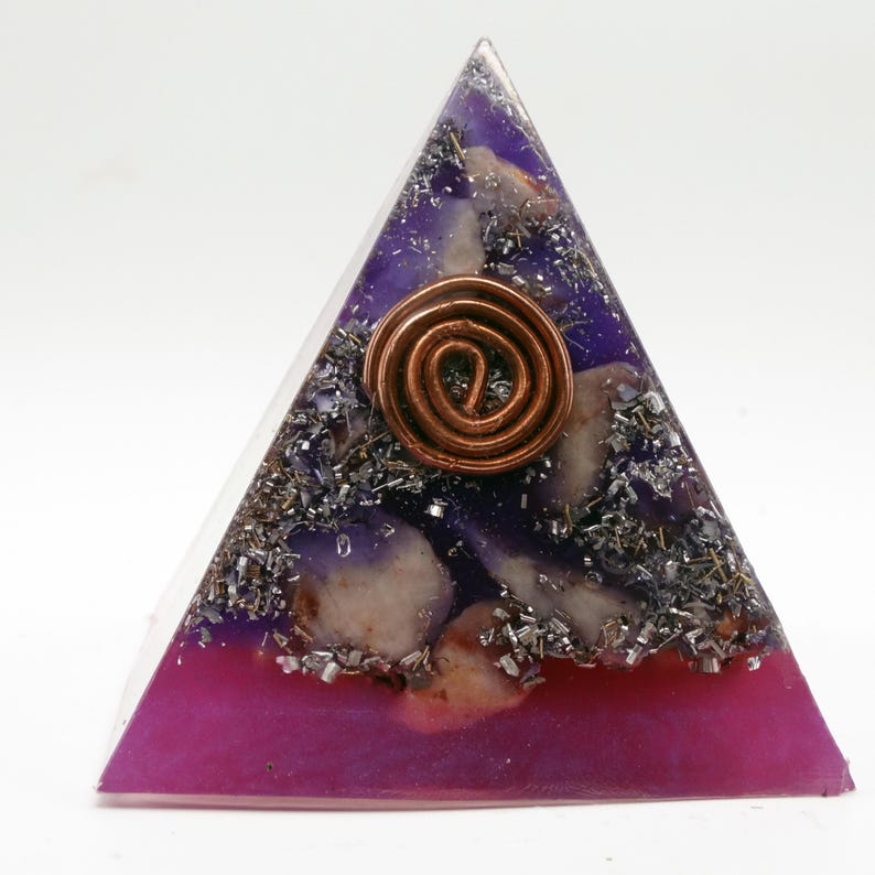 May include: A pyramid-shaped orgone energy generator with a copper coil at the center. The pyramid features layers of purple and magenta resin, with embedded crystals and metallic flakes. The pyramid is a spiritual and decorative item.