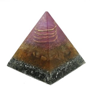 May include: A pyramid-shaped orgone energy generator. The top is a translucent purple with a copper coil. The middle section is amber with embedded stones. The base is black with a crystalline appearance. This decorative piece is designed to promote positive energy.