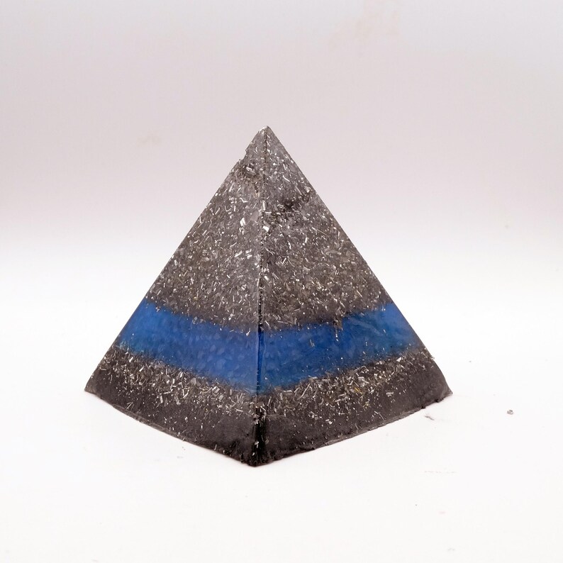 Peut inclure: Un objet d&eacute;coratif en forme de pyramide avec un ext&eacute;rieur mouchet&eacute; gris fonc&eacute; et argent&eacute;. Une bande bleue horizontale est visible au centre. La pyramide est pos&eacute;e sur un fond blanc.
