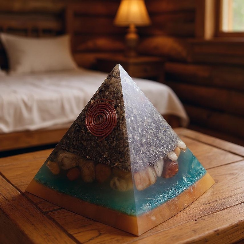May include: A decorative pyramid with a copper coil and embedded stones. The pyramid has a clear, blue, and tan resin base. The top portion is a mix of dark and light materials.