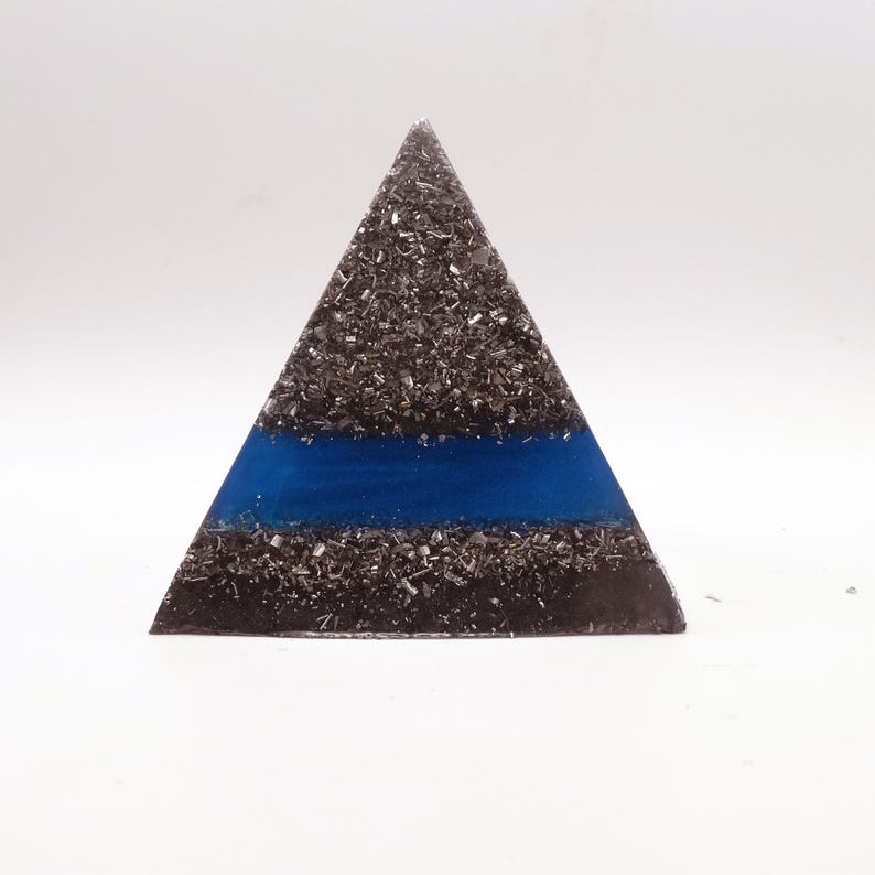 Peut inclure: Une pi&egrave;ce d'art triangulaire en r&eacute;sine avec une fine bande bleue. La forme pyramidale est remplie de petits fragments m&eacute;talliques gris fonc&eacute;. La bande bleue est centr&eacute;e horizontalement sur la pyramide.