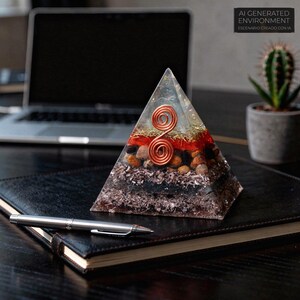 May include: A clear resin pyramid with layers of stones, copper wire, and red and gold accents. The pyramid sits on a black leather-bound notebook with a silver pen. The text "AI GENERATED ENVIRONMENT ESCENARIO CREADO CON IA" is in the background.
