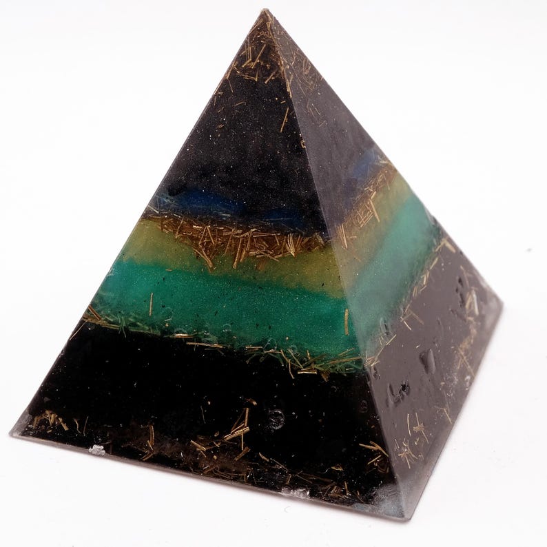 May include: A layered pyramid sculpture with a black base, transitioning to green, yellow, and blue bands. The pyramid is embedded with gold-colored strands, creating a unique, geometric art piece.