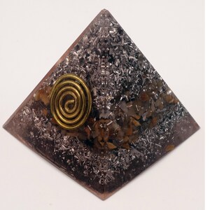 May include: A pyramid-shaped orgone energy generator. The pyramid is a dark purple color with a brass spiral and embedded metal shavings. The pyramid is a decorative item.