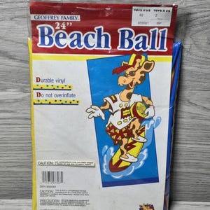 May include: A 24-inch beach ball featuring Geoffrey the Giraffe from Toys "R" Us. The ball is red, yellow, and blue with a white outline. The ball is packaged in a clear plastic bag with a red, white, and blue label.