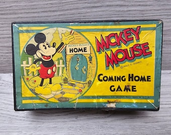 May include: Vintage Mickey Mouse board game box featuring a cartoon image of Mickey Mouse walking towards his home. The box is yellow with red and black lettering that reads "Mickey Mouse Coming Home Game" and "Walt E. Disney".