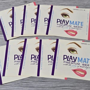 Puede incluir: Varias etiquetas de cerveza Playmate Premium vintage. Cada etiqueta presenta una ilustración de un ojo y labios de mujer, con el nombre de la marca en azul y el texto "Premium Beer".