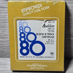 Puede incluir: Una caja amarilla vintage de cartucho de 8 pistas en blanco "Audition". La caja presenta el texto "IMPROVED! QUALITY LOW NOISE" y un gráfico del número "80" en azul. La caja también incluye el texto "MADE IN U.S.A. BY COLUMBIA MAGNETICS".