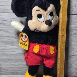 May include: A vintage plush Mickey Mouse toy with black fur, red shorts, yellow shoes, and a tag that reads "Come alive Puppet toy".