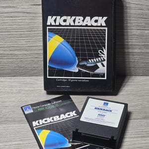 May include: A black box and cartridge for the Atari 400/800 computer game "Kickback." The box features a blue and yellow football graphic with a soccer shoe kicking the ball. The game cartridge and instructions are also visible.