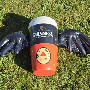 May include: A black inflatable beer stein with wings. The stein is decorated with the Guinness Draught logo and a Bass Pale Ale logo.