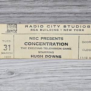 Pode incluir: Um bilhete vintage para o programa de jogos de televisão da NBC "Concentration" estrelado por Hugh Downs. O bilhete é datado de 31 de março de 1959 e indica que as portas fecham às 11:15 AM. O bilhete é para um espetáculo nos estúdios Radio City da cidade de Nova Iorque.