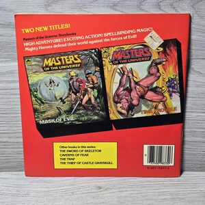 Puede incluir: Contraportada de dos libros de cuentos vintage de "Masters of the Universe". La cubierta roja presenta los t&iacute;tulos "Mask of Evil" y "Time Trouble" con ilustraciones llenas de acci&oacute;n. Otros t&iacute;tulos de la serie se enumeran en un rect&aacute;ngulo amarillo.