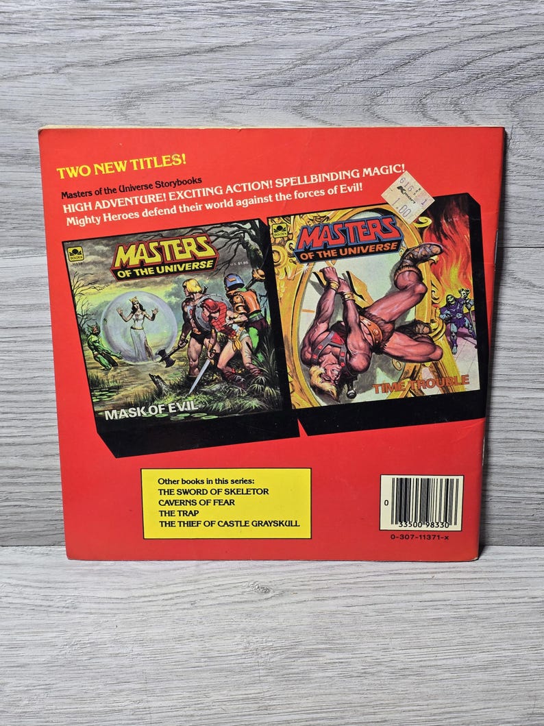Puede incluir: Contraportada de dos libros de cuentos vintage de "Masters of the Universe". La cubierta roja presenta los t&iacute;tulos "Mask of Evil" y "Time Trouble" con ilustraciones llenas de acci&oacute;n. Otros t&iacute;tulos de la serie se enumeran en un rect&aacute;ngulo amarillo.