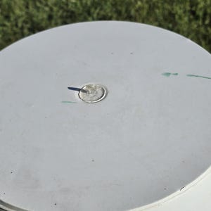 May include: White plastic lid with a small, round, clear plastic plug in the center. The lid has a few light green marks on the surface.