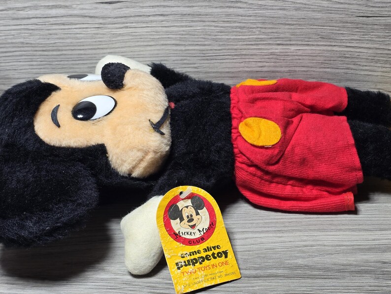 May include: A black and red plush Mickey Mouse puppet with a yellow circle on the red shorts. The puppet has a tag that says "Come alive Puppet toy Two toys in one Mickey Mouse Club".