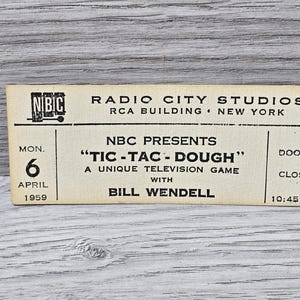 Pode incluir: Um bilhete branco para o programa de jogos de televisão da NBC "Tic-Tac-Dough", apresentado por Bill Wendell. O espetáculo terá lugar na segunda-feira, 6 de abril de 1959, nos estúdios Radio City de Nova Iorque. As portas abrem às 10:45 AM.