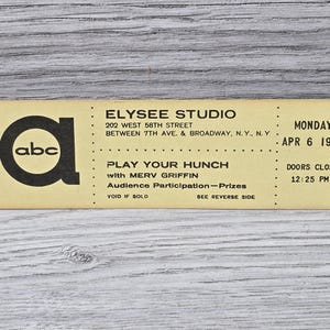 Pode incluir: Um bilhete amarelo e preto para o programa de televisão ABC "Play Your Hunch" com Merv Griffin. O show será realizado no Elysee Studio na cidade de Nova York na segunda-feira, 6 de abril de 1959. O bilhete indica que as portas fecham às 12:25 PM.
