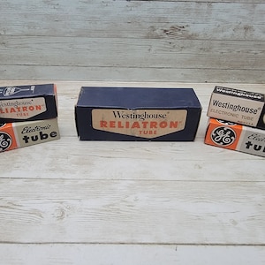 May include: Three vintage boxes for electronic tubes. The boxes are all brown and white with black lettering. The top box says "Westinghouse Reliatron Tube". The middle box says "Electronic Tube" and the bottom box says "Westinghouse Electronic Tube".