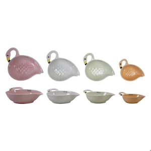 May include: A collection of ceramic swan-shaped measuring cups and spoons in pastel shades. The set includes pink, white, green, and orange pieces. The swan-shaped measuring cups are labeled with measurements.