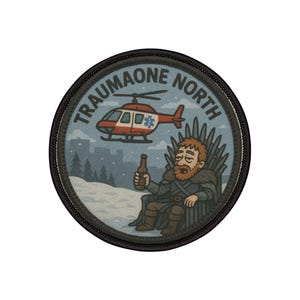 May include: Round patch with the text "TRAUMAONE NORTH" encircling a cartoon image. The image features a red and white helicopter, a bearded figure on a throne holding a bottle, and a snowy landscape. The patch has a black border.