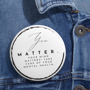 Könnte beinhalten: Weißer Knopf mit schwarzem Text, der "You Matter. Your mind matters! Take care of your mental health." lautet.