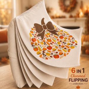 May include: A beige fabric item with a layered, fan-like structure featuring a large pumpkin-shaped graphic composed of smaller autumn-themed icons like leaves, acorns, and mushrooms, topped with a brown bow and the text 6 IN 1 Charmed FLIPPING collection.