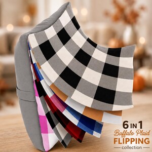 May include: A gray pillow with a fan of six interchangeable fabric covers in buffalo plaid patterns. The colors include black and white, tan and white, blue and white, red and white, pink and white, and black and white. Text reads 6 IN 1 Buffalo Plaid FLIPPING collection.